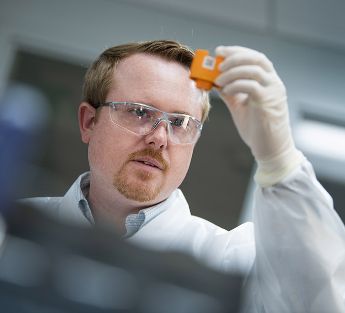 Photo of Kyle Parker inspecting a reagent cartridge prior to loading clinical samples for analysis with a point-of-care device.