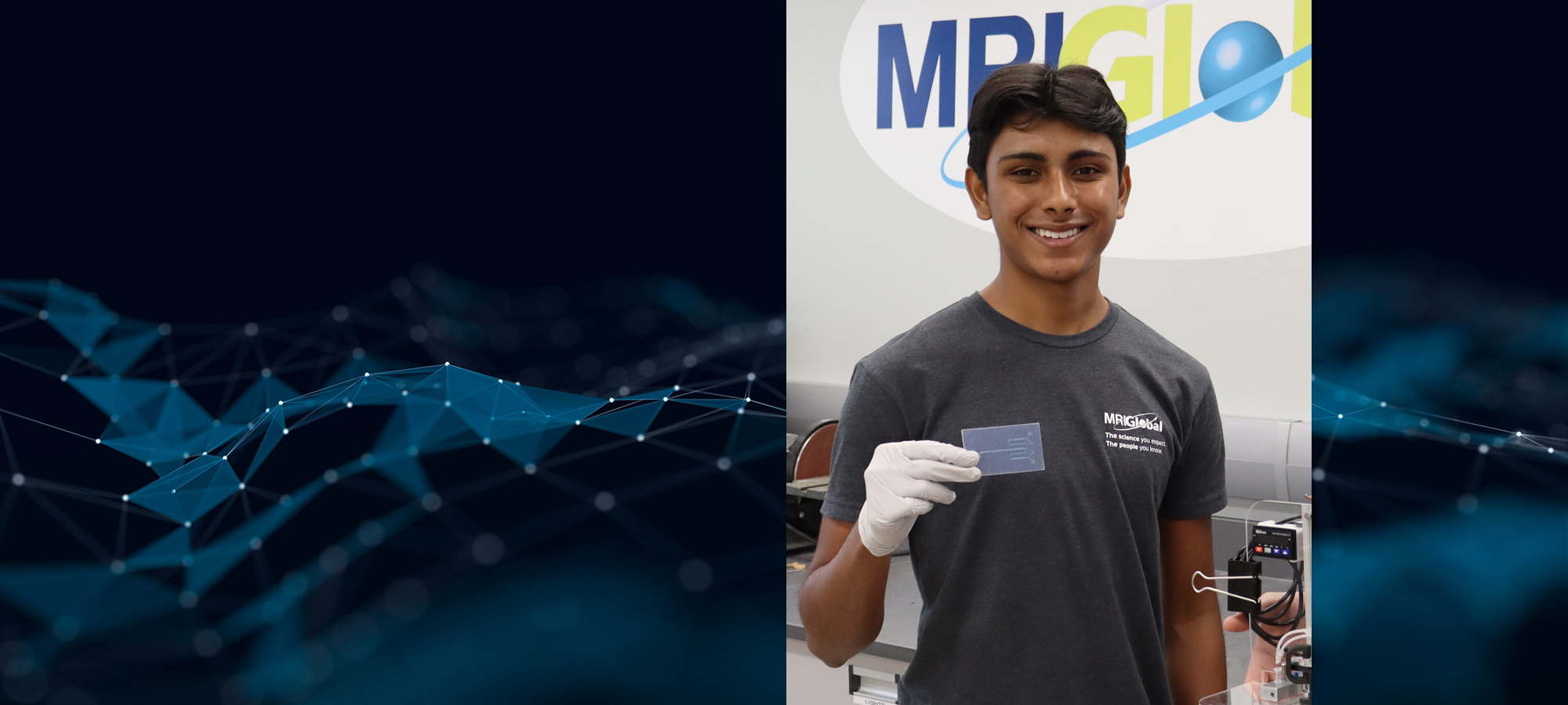 Arjun Garapaty Holding Microfluidic Device in Engineering Lab MRIGlobal