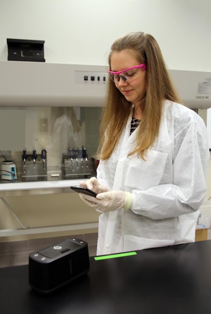 Jen Stone three9 in lab - female scientist holding device that detects COVID-19
