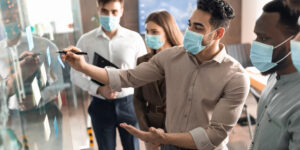 Staff with masks in front of board with notes 300x150